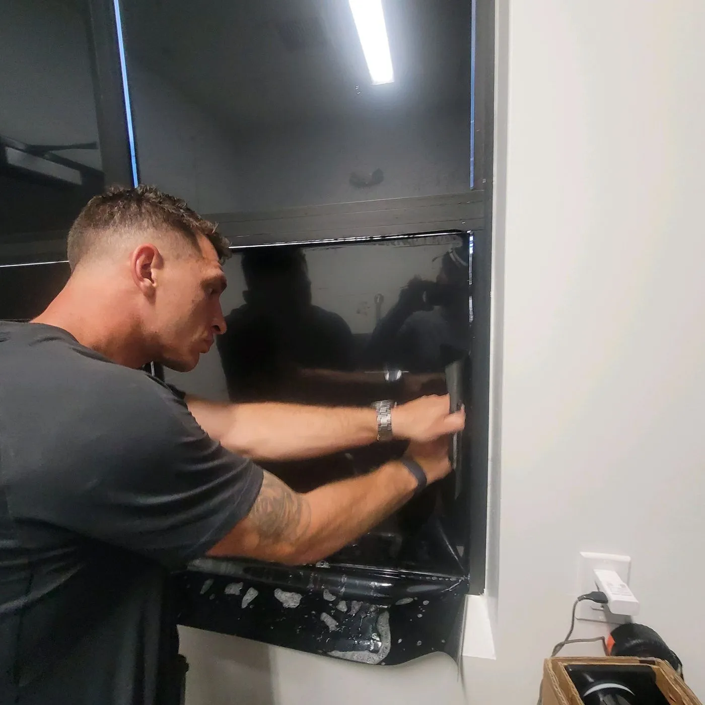 Technician squeegeeing corner of large tinted panel