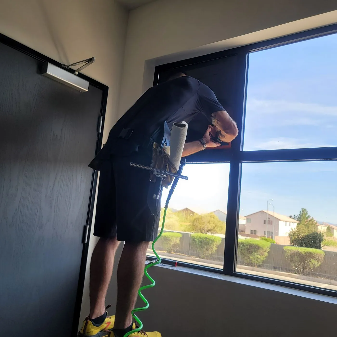 Technician trimming edge of solar film commercial window