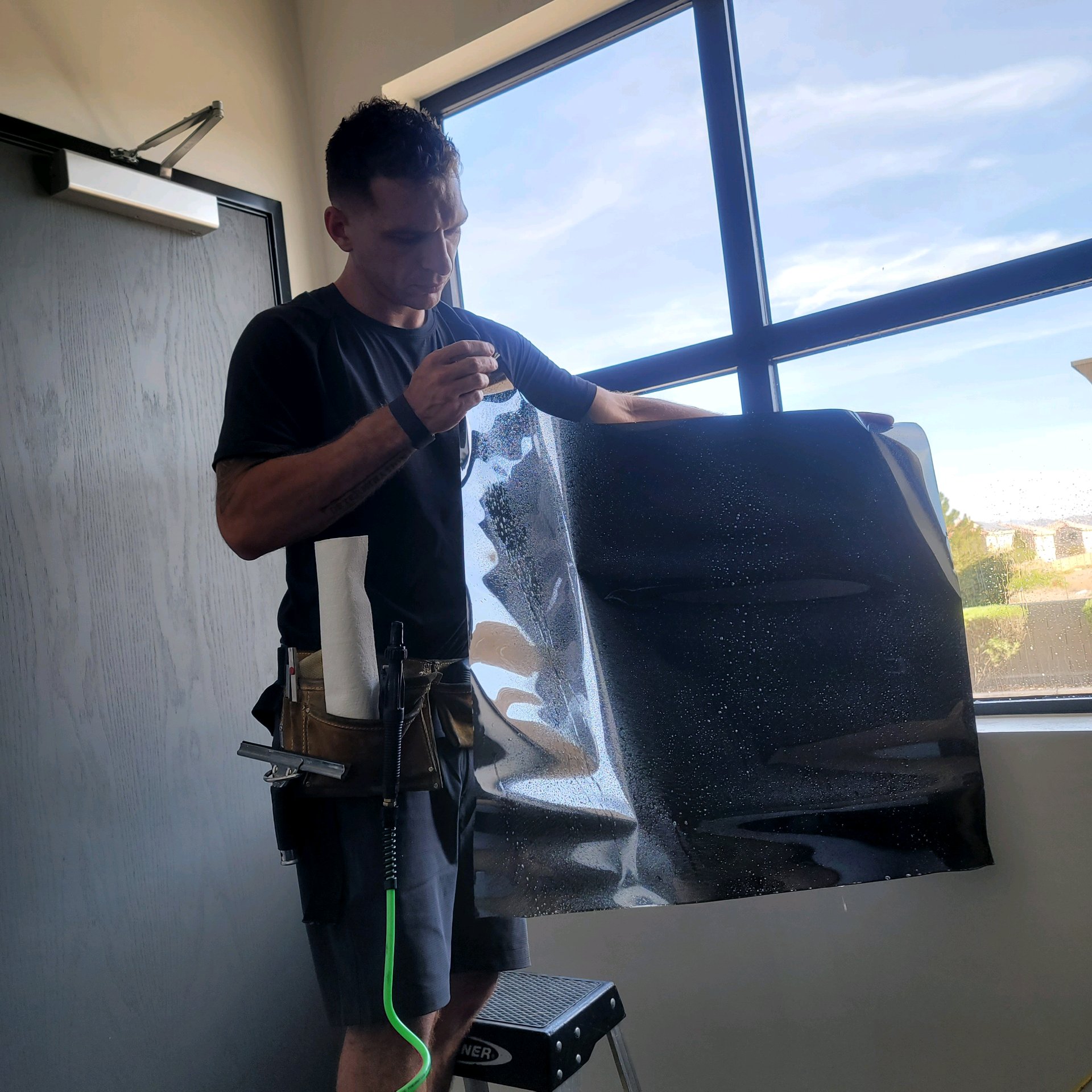 Technician peeling liner off dark solar window film