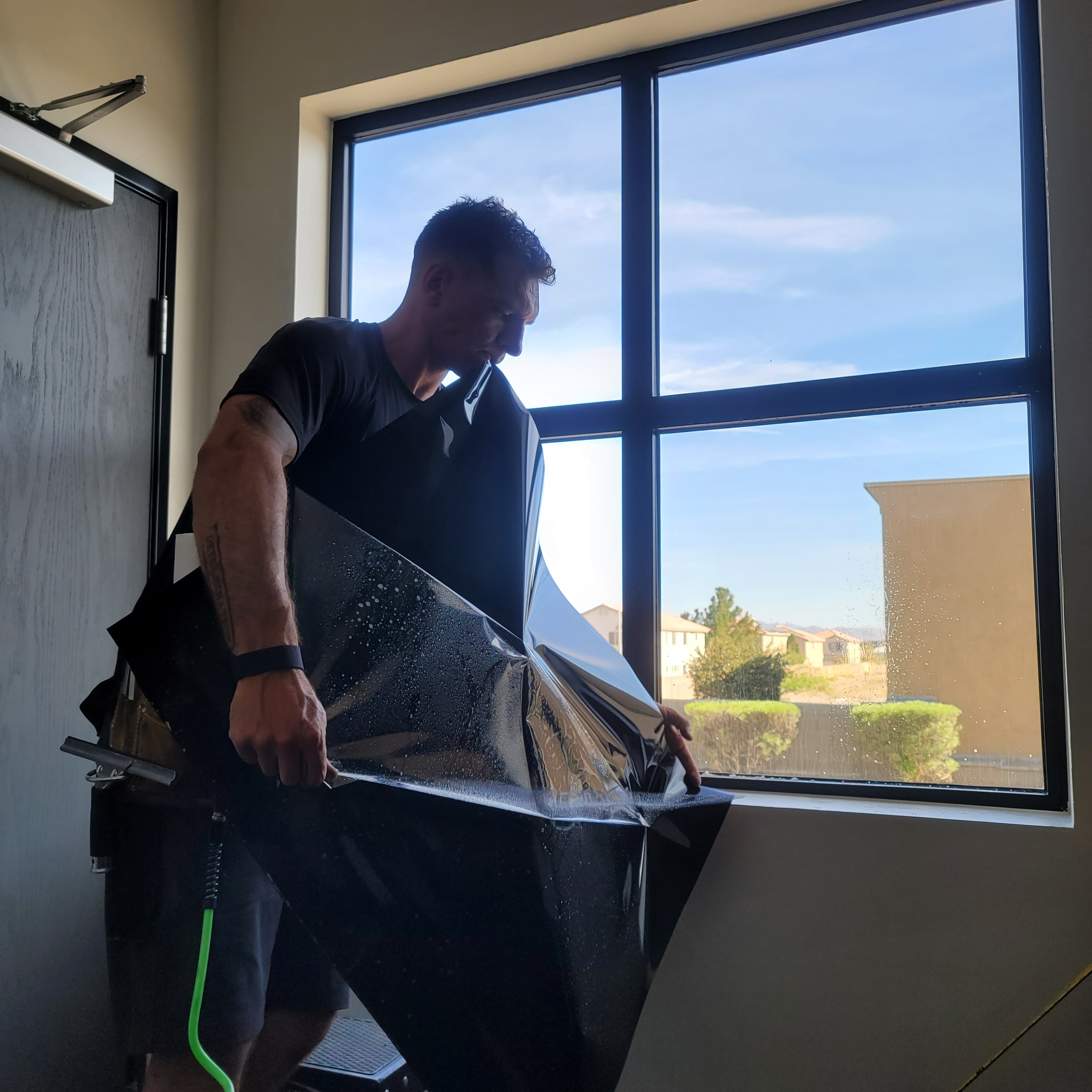 Technician holding large dark film panel before application