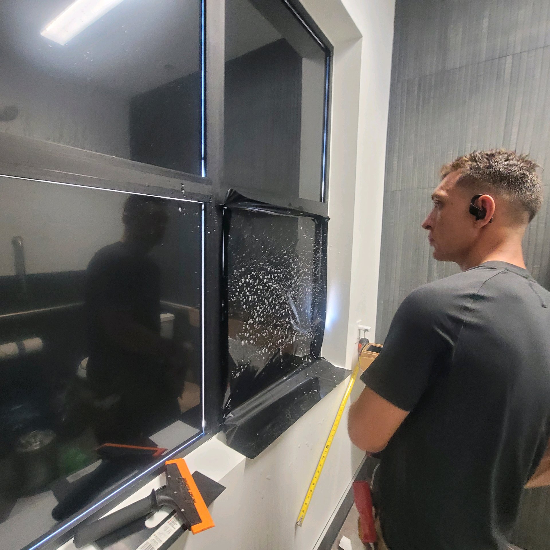 Technician inspecting freshly applied solar film with tape measure