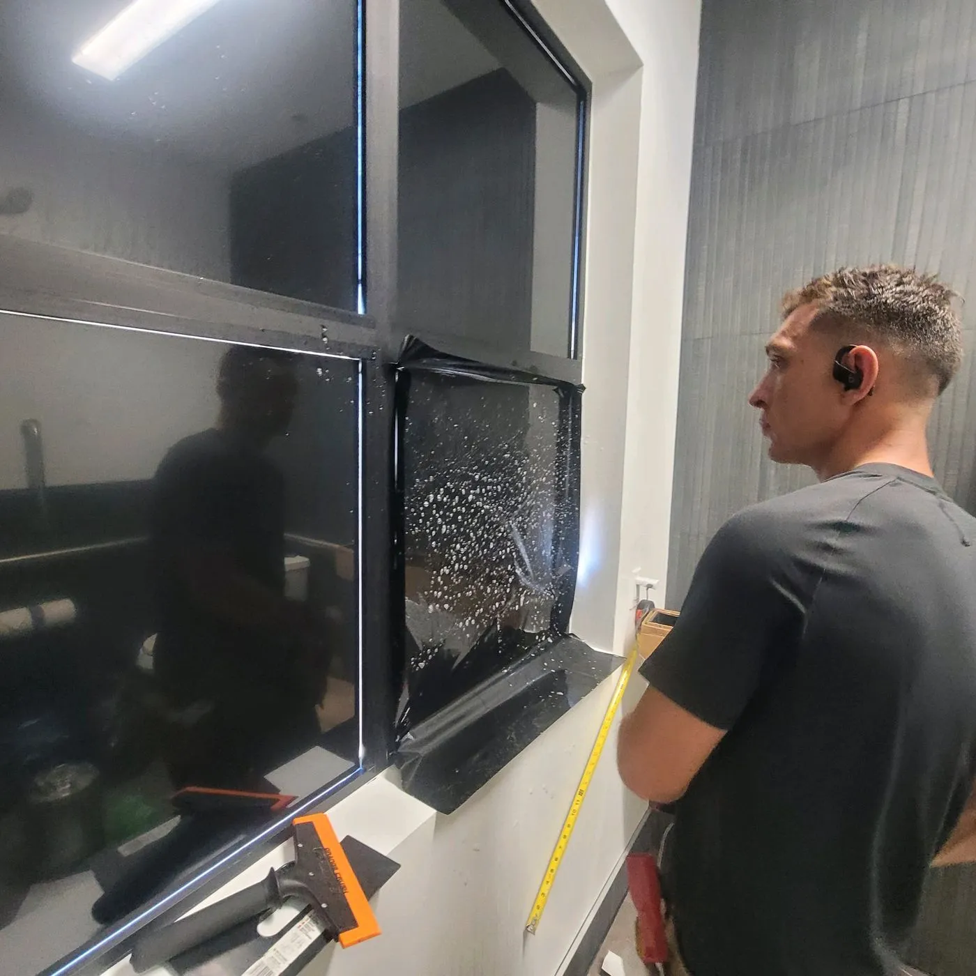 Technician inspecting freshly applied solar film with tape measure
