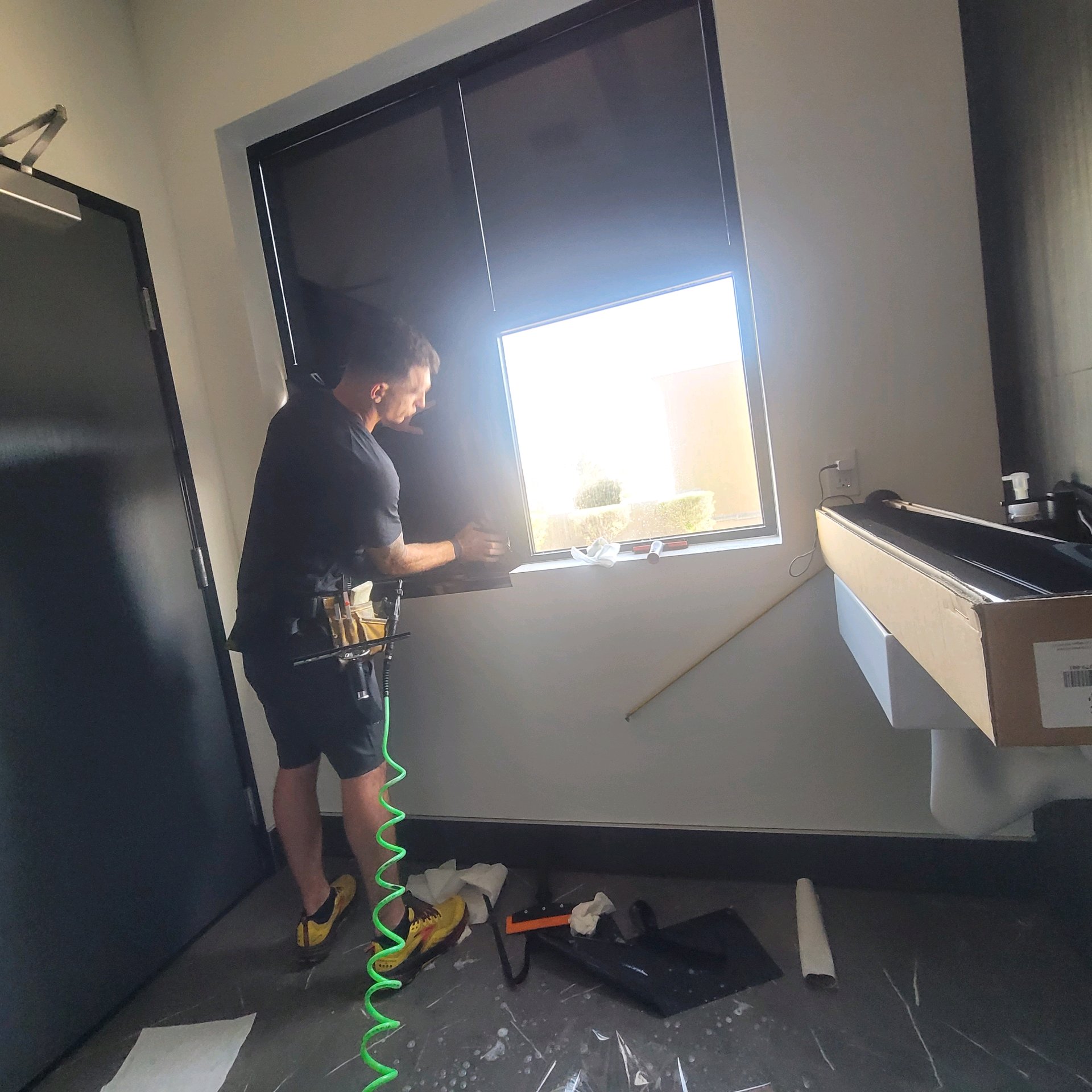 Technician squeegeeing small commercial window solar film