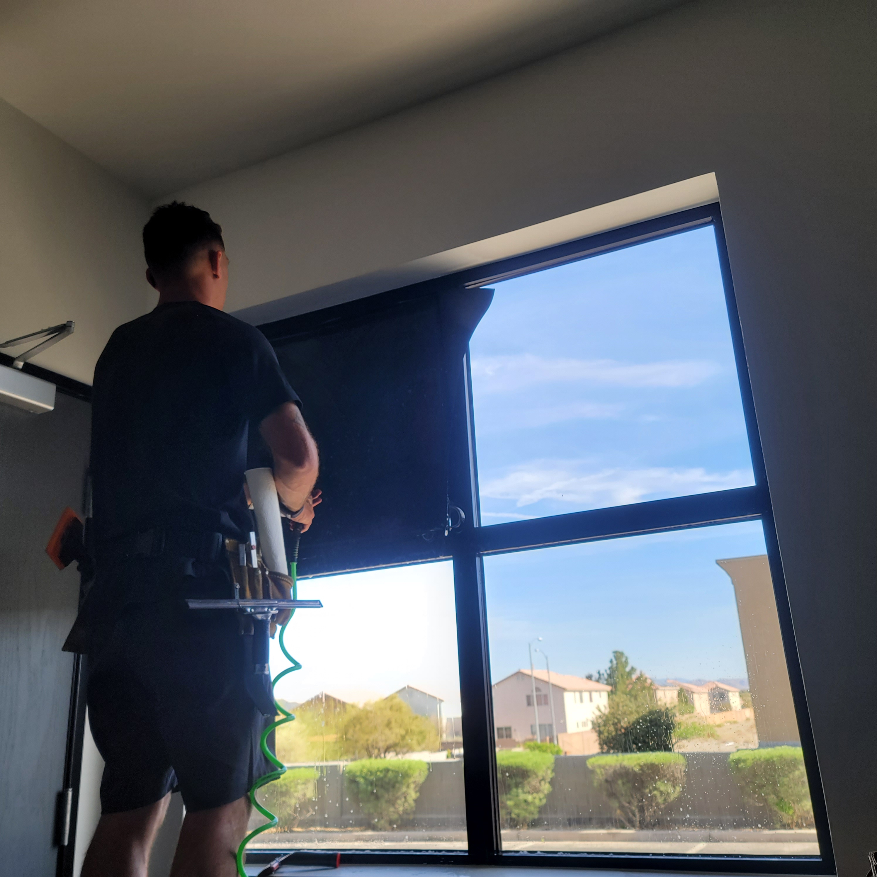 Technician squeegeeing solar film onto commercial window