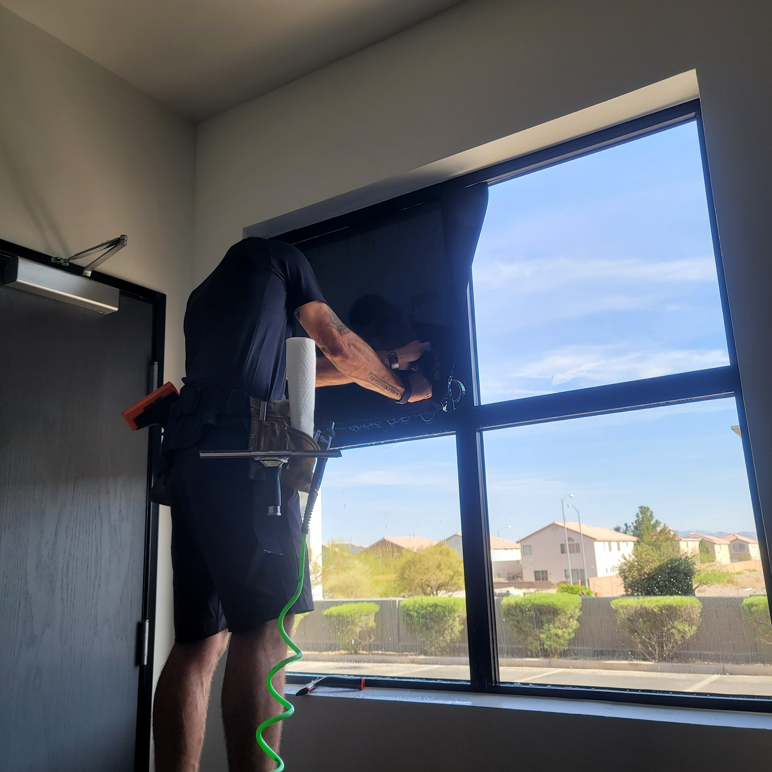 Technician squeegeeing solar film commercial window half done