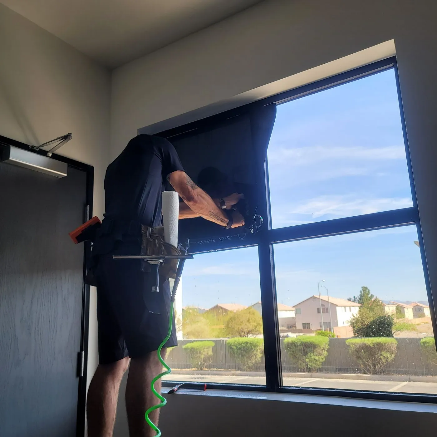 Technician squeegeeing solar film commercial window half done